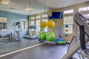 a gym with a lot of exercise equipment and mirrors on the wall